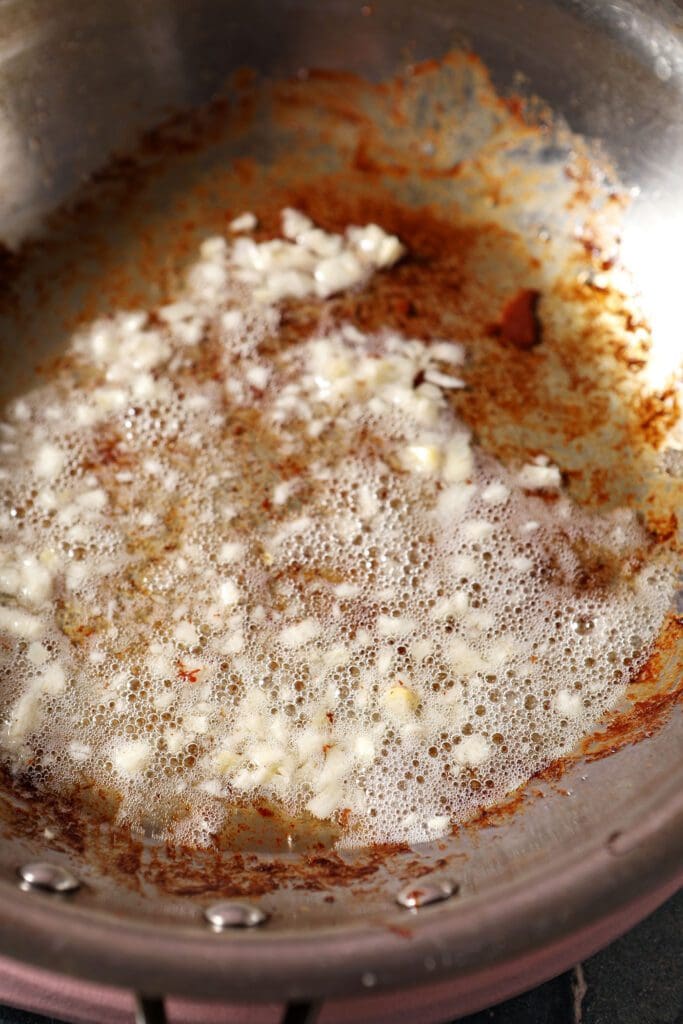 Garlic sizzles in bacon grease in a skillet