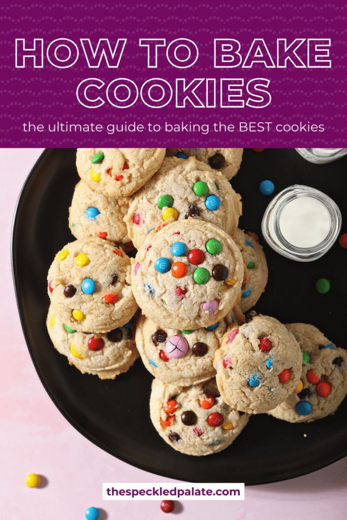 A black plate holds M&M cookies and a glass of milk with the text how to bake cookies the ultimate guide to baking the BEST cookies