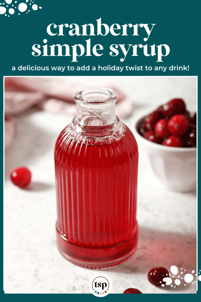 A ribbed glass jar of cranberry simple syrup with cranberries around it on marble with the text cranberry simple syrup a delicious way to add a holiday twist to any drink