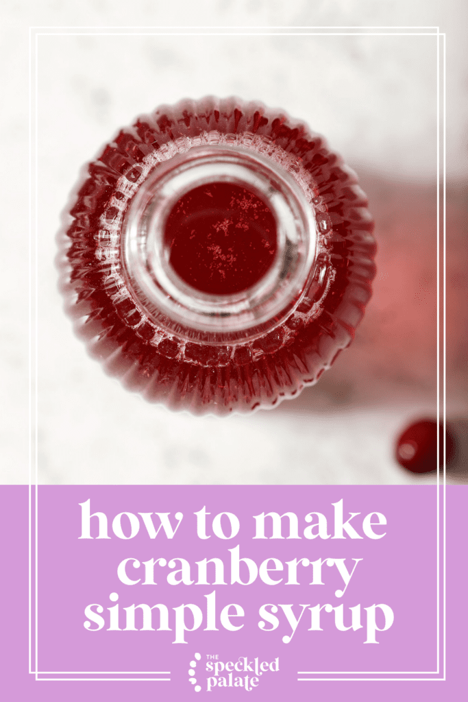 Overhear of a glass jar holding cranberry syrup on marble with the text how to make cranberry simple syrup