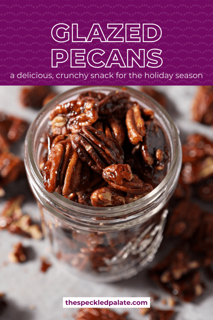 A glass jar of glazed pecans on top of a sheet pan with more pecans with the text glazed pecans a delicious, crunchy snack for the holiday season