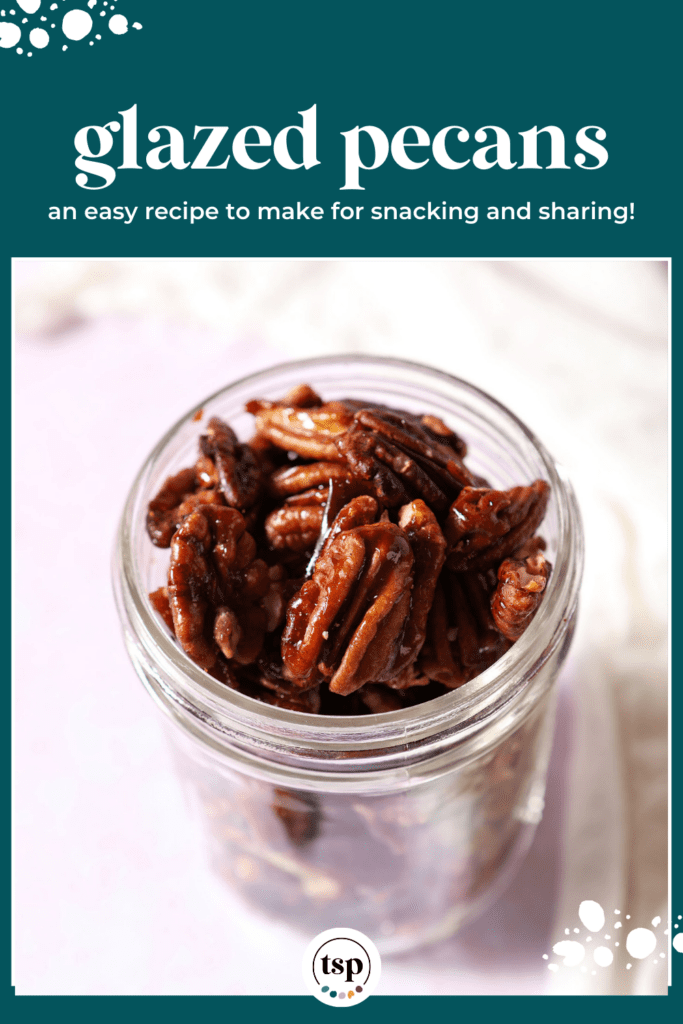 A mason jar of glazed pecans on a pink surface next to a white linen with the text glazed pecans an easy recipe to make for snacking and sharing