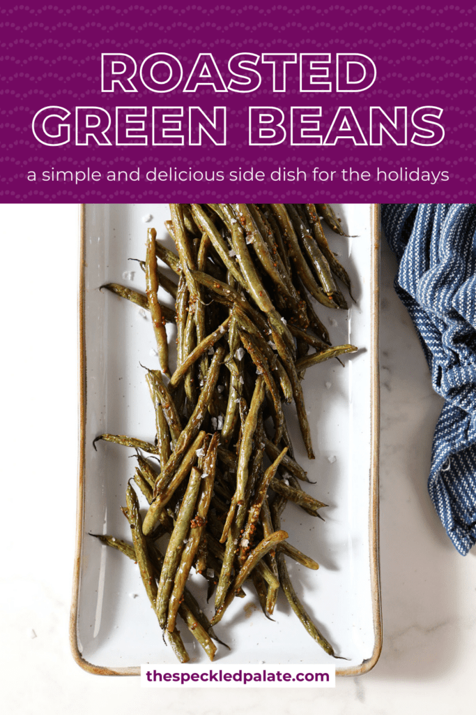 Roasted green beans on a white platter next to a blue linen on marble with the text roasted green beans a simple and delicious side dish for the holidays