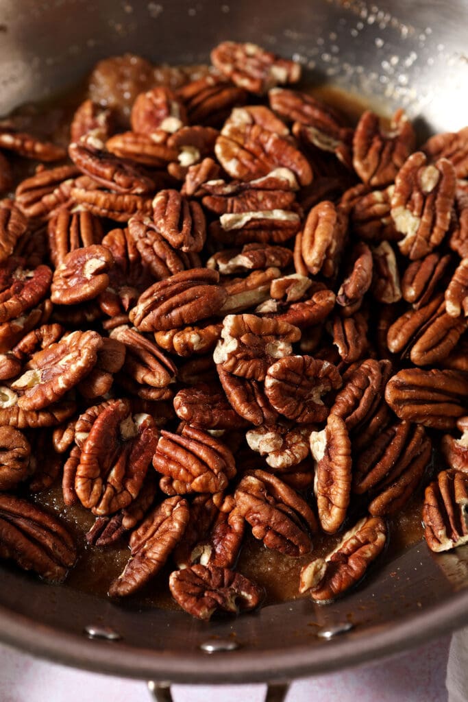 Pecans in a skillet on top of glaze