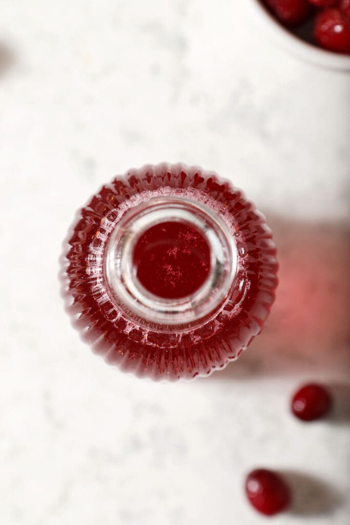 Overhear of a glass jar holding cranberry syrup on marble