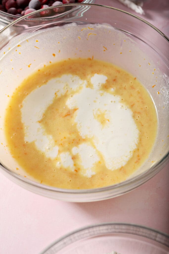 Milk sits on top of orangey yellow ingredients in a bowl on a pink surface