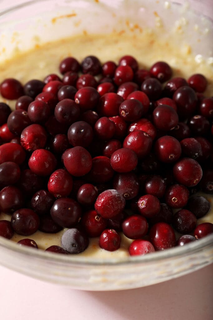 Cranberries on top of muffin batter in a bowl