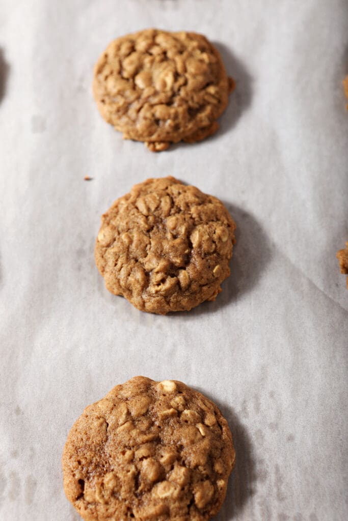 Baked Cinnamon Oatmeal Cookies on a parchment-lined cookie sheet