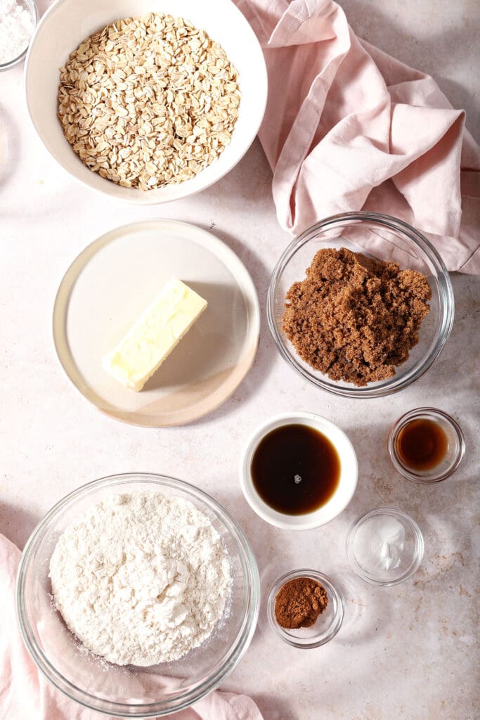 Ingredients to make oatmeal cookies in bowls on a stone surface