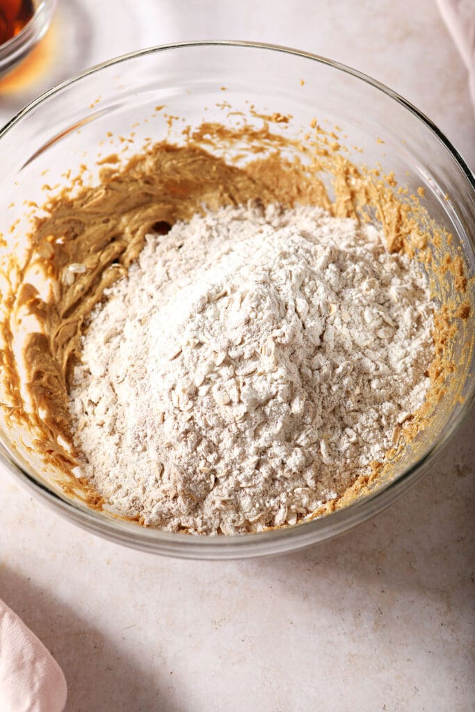 Dry ingredients are added to the wet ingredients in a bowl for cinnamon oatmeal cookies