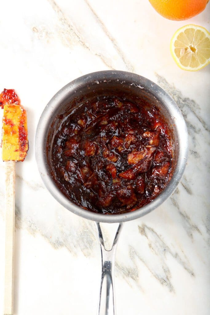 Orange cranberry compote in a saucepan on marble after cooking down