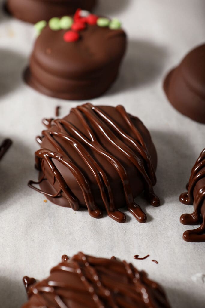 Drizzled chocolate on top of Chocolate Covered Ritz Crackers on a parchment-lined sheet pan