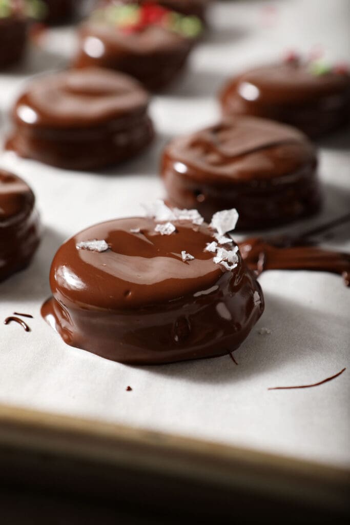 Wet Ritz Cracker Cookies coated in chocolate on a parchment-lined sheet pan