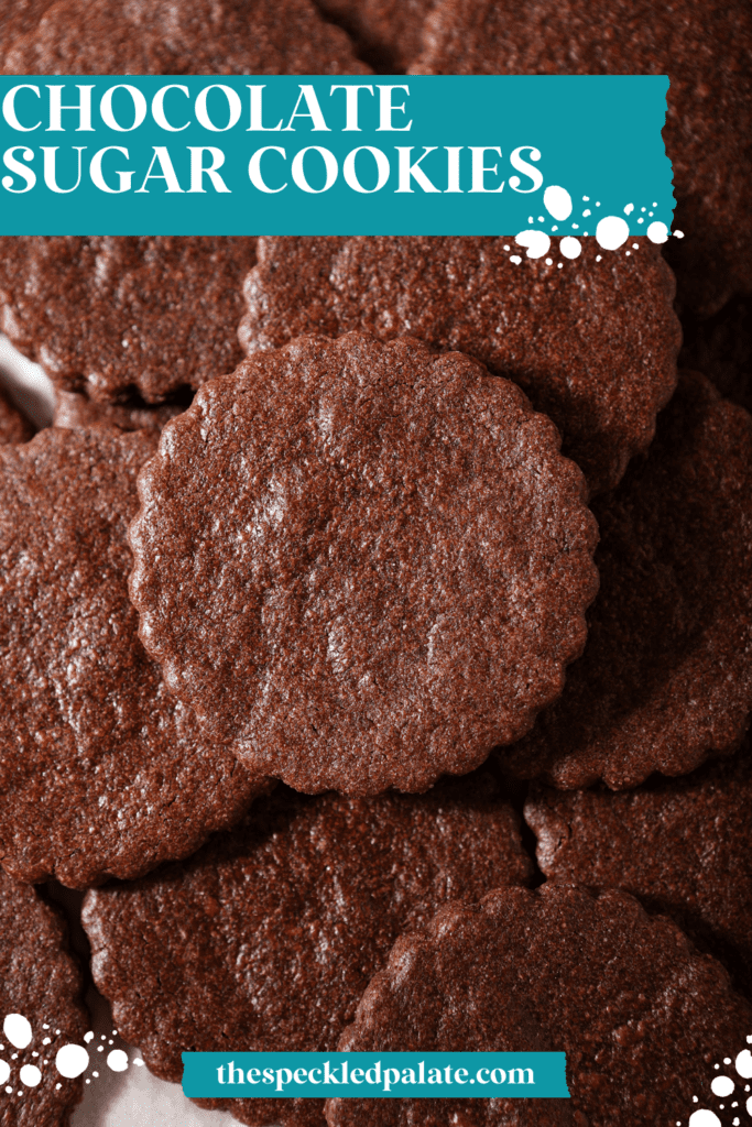 Several scalloped chocolate sugar cookies on a sheet pan stacked on top of each other with the text chocolate sugar cookies