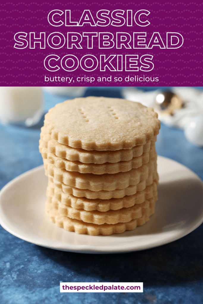 scalloped cookies stacked on a white plate on a blue surface with the text classic shortbread cookies buttery, crisp and so delicious