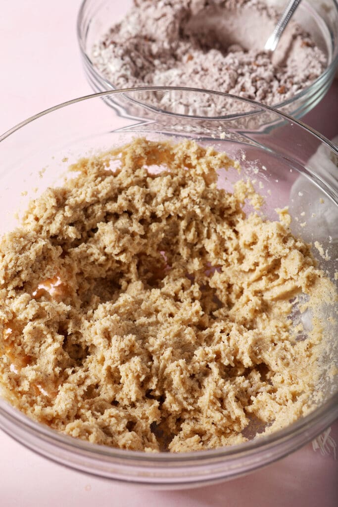 Wet ingredients for chocolate sugar cookies in a bowl on a pink surface