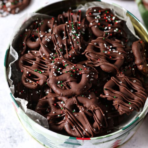 Overhead of a Christmas tree tin of chocolate covered pretzels with Christmas sprinkles