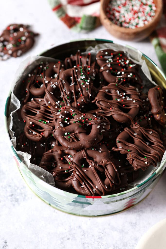 Overhead of a Christmas tree tin of chocolate covered pretzels with Christmas sprinkles