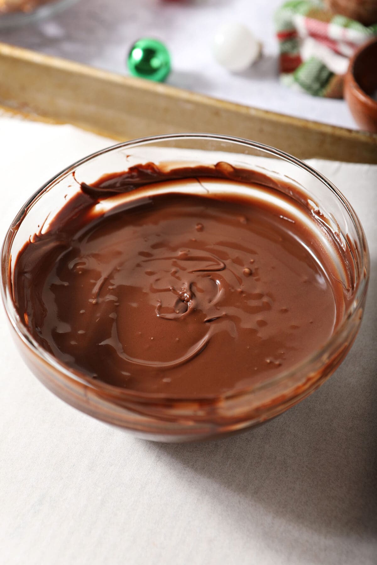 A bowl of melted chocolate on a parchment-lined sheet pan