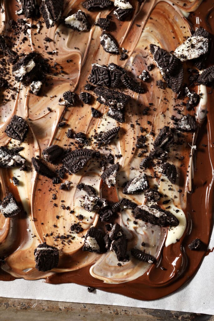 Oreos on top of white and dark chocolate on a sheet pan