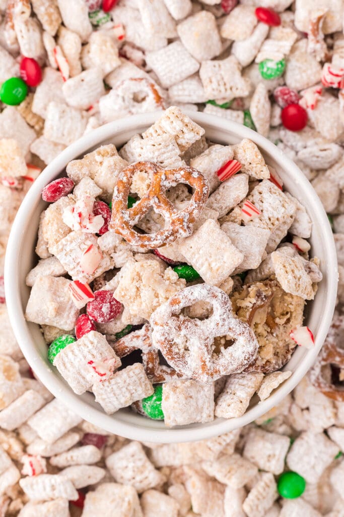 A bowl of reindeer chow on a sheet pan of more reindeer chow