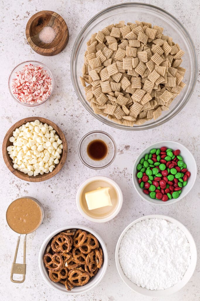 Ingredients to make Christmas Puppy Chow in bowls on a pinkish surface