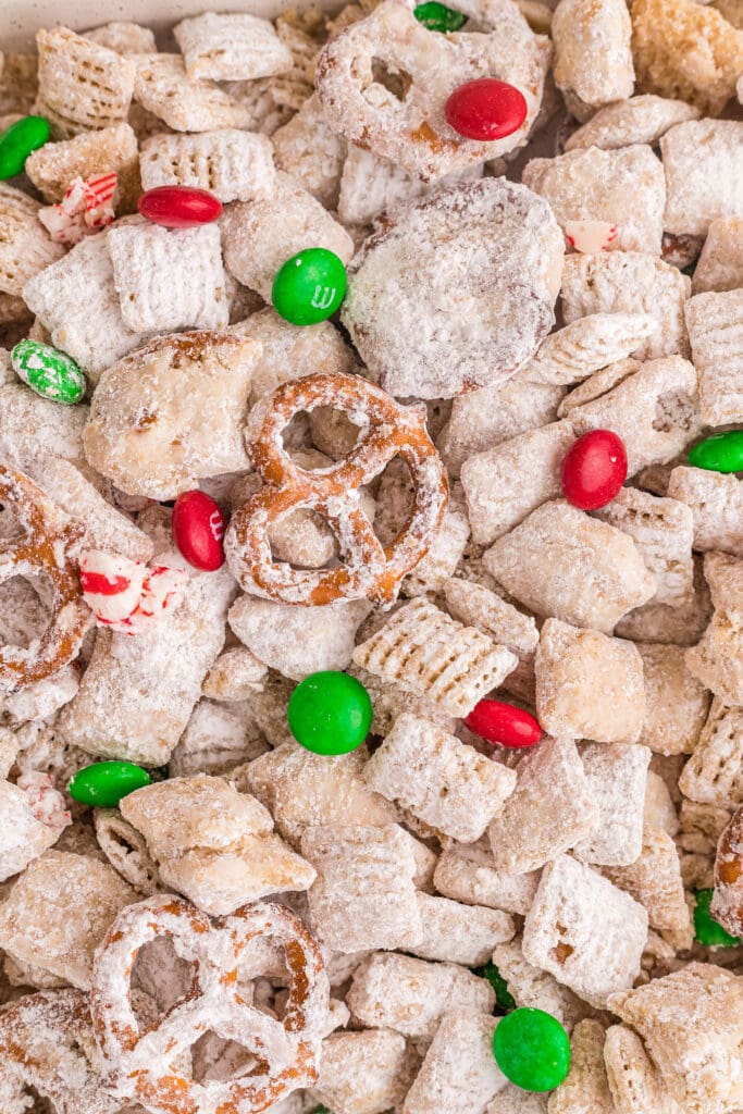 Close up of Christmas Puppy Chow on a sheet pan with pretzels and M&Ms