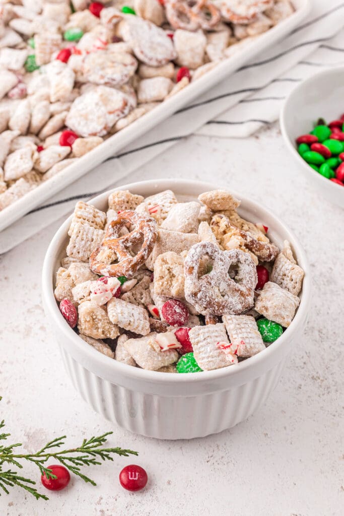 A small bowl of reindeer chow in a bowl next to a sheet pan of more