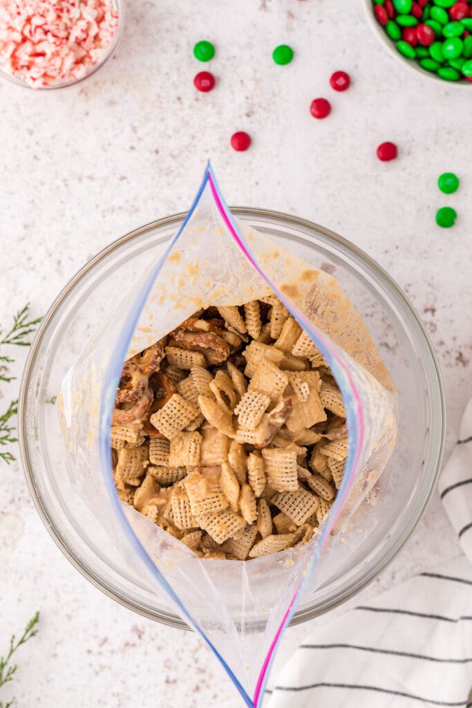 White chocolate and peanut butter coated Chex cereal and pretzels in a large bag