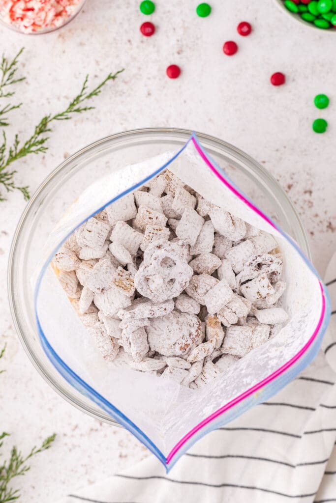 Powdered sugar on top of puppy chow in a bag inside a bowl