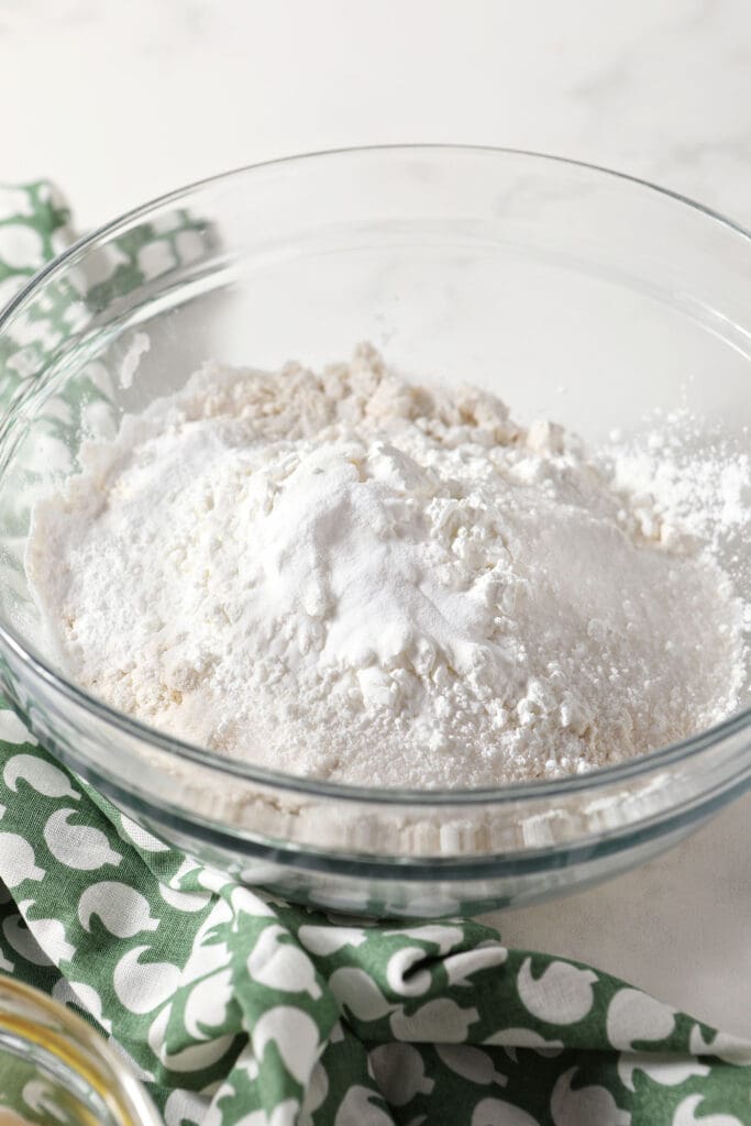 Dry waffle ingredients in a bowl with a green linen on marble