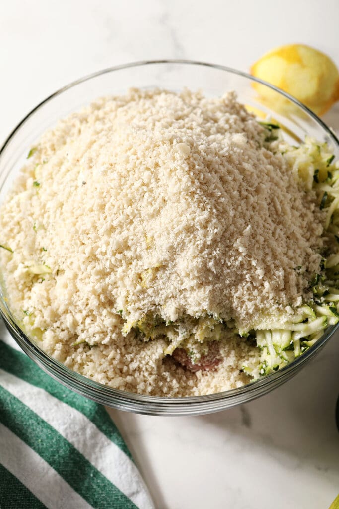 Breadcrumbs on top of ingredients for meatballs in a bowl on marble