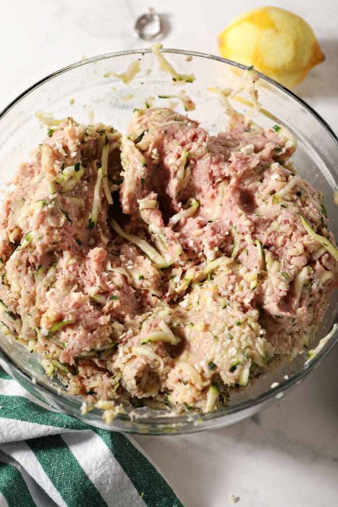 Mixed ingredients to make baked turkey zucchini meatballs in a glass bowl before forming