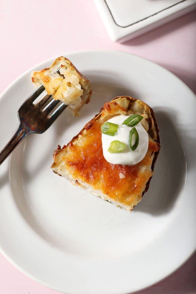 A sliced twice baked potato on a white plate with a fork