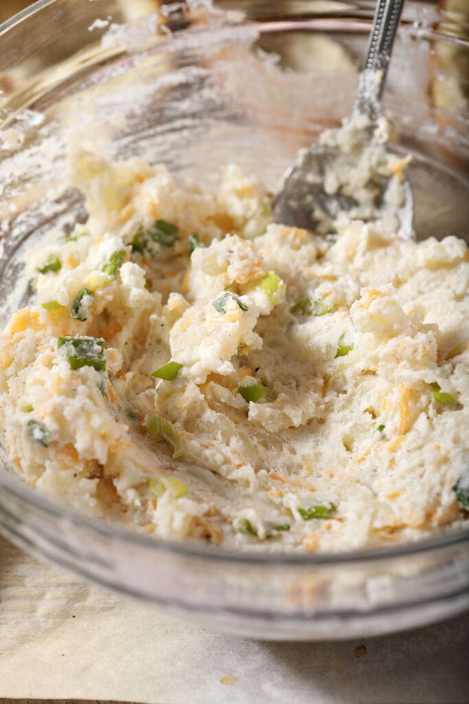 The filling for a twice baked potato recipe in a bowl with a spoon