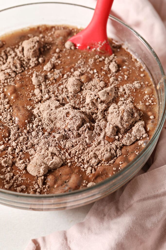 Waffle batter ingredients before mixing in a bowl with a red spatula