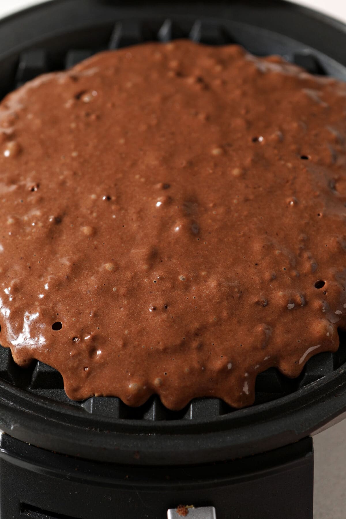 Chocolate waffle batter in a waffle iron before cooking