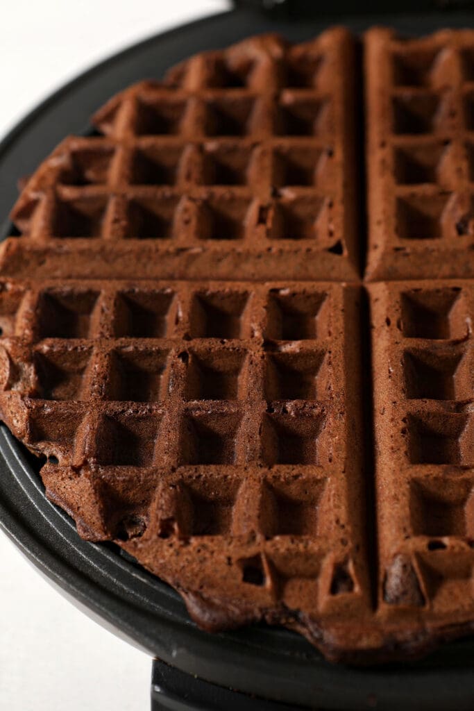 A chocolate waffle in a waffle iron before it is served