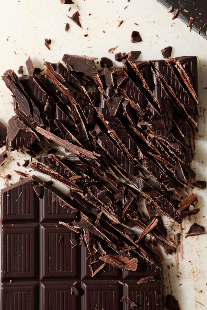 A chopped chocolate bar on a white cutting board