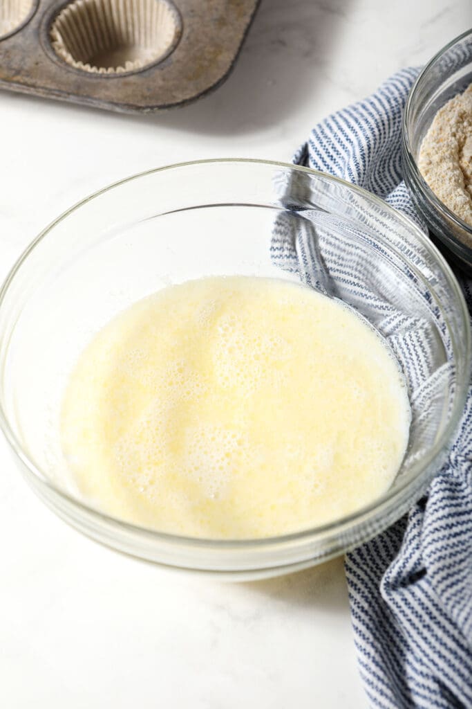 Mixed butter and sugar and milk in a bowl next to a striped blue and white towel