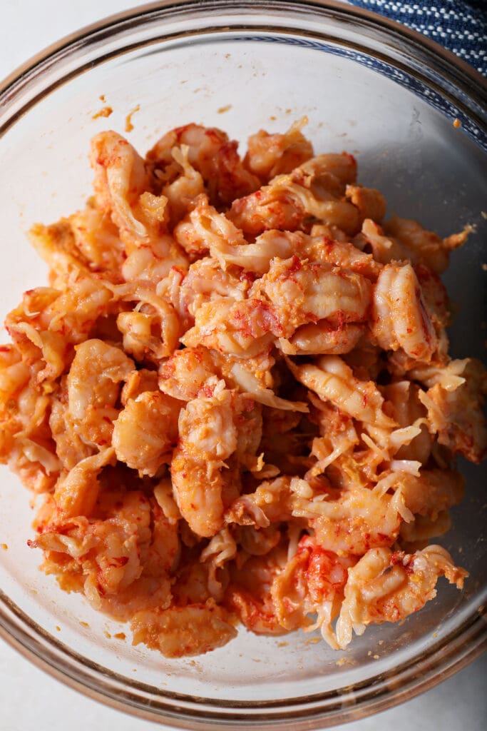 a bowl of seasoned crawfish tails on a marble surface