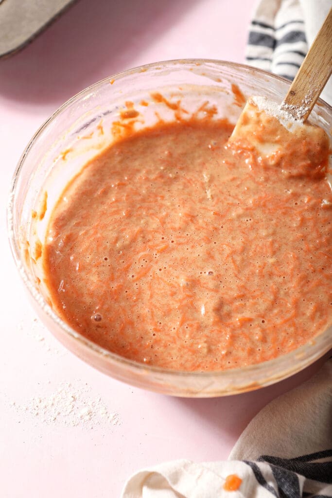 Carrot cupcake batter in a bowl on a pink surface