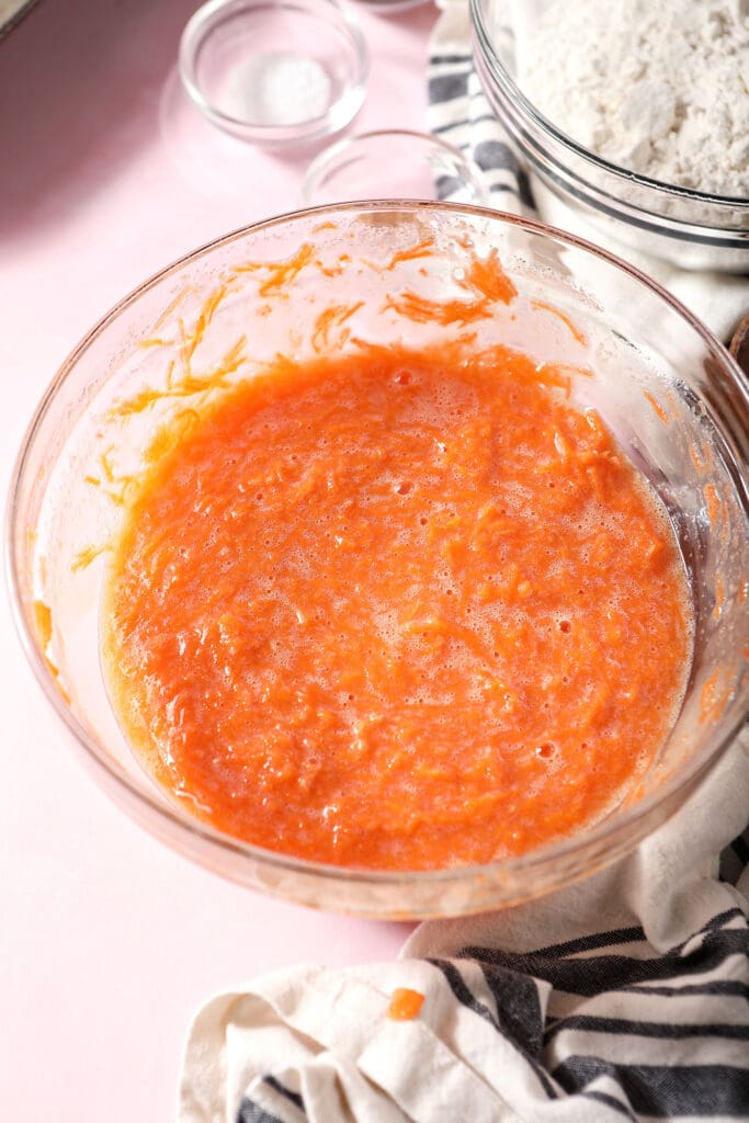 Wet ingredient with carrots in a bowl on a pink surface