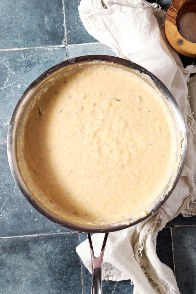 cheese grits in a saucepan on a tiled turquoise surface with a white linen