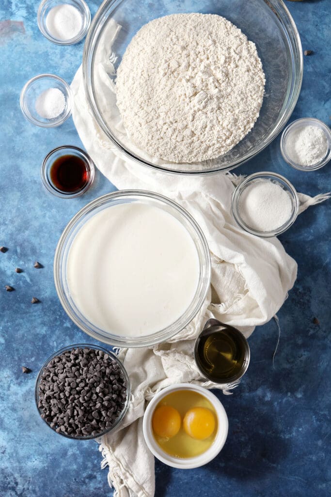 ingredients to make buttermilk waffles with chocolate chips on a blue surface with white linens