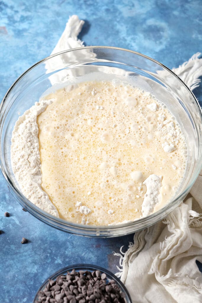 the buttermilk mixture is added to the bowl with flour on a dark blue countertop