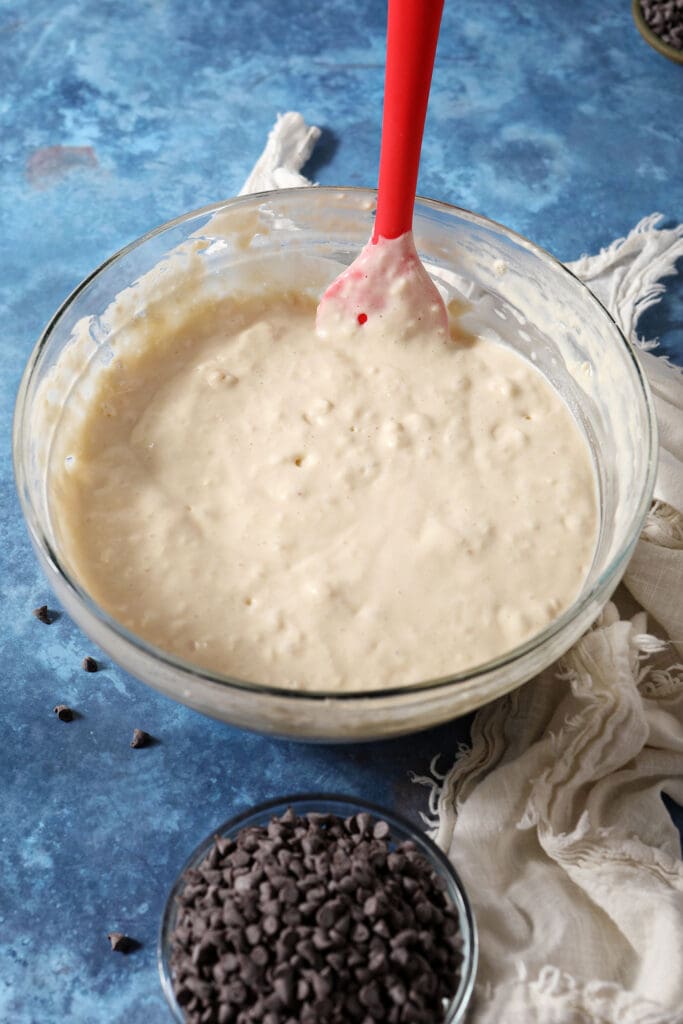 a red rubber spatula stirs waffle batter