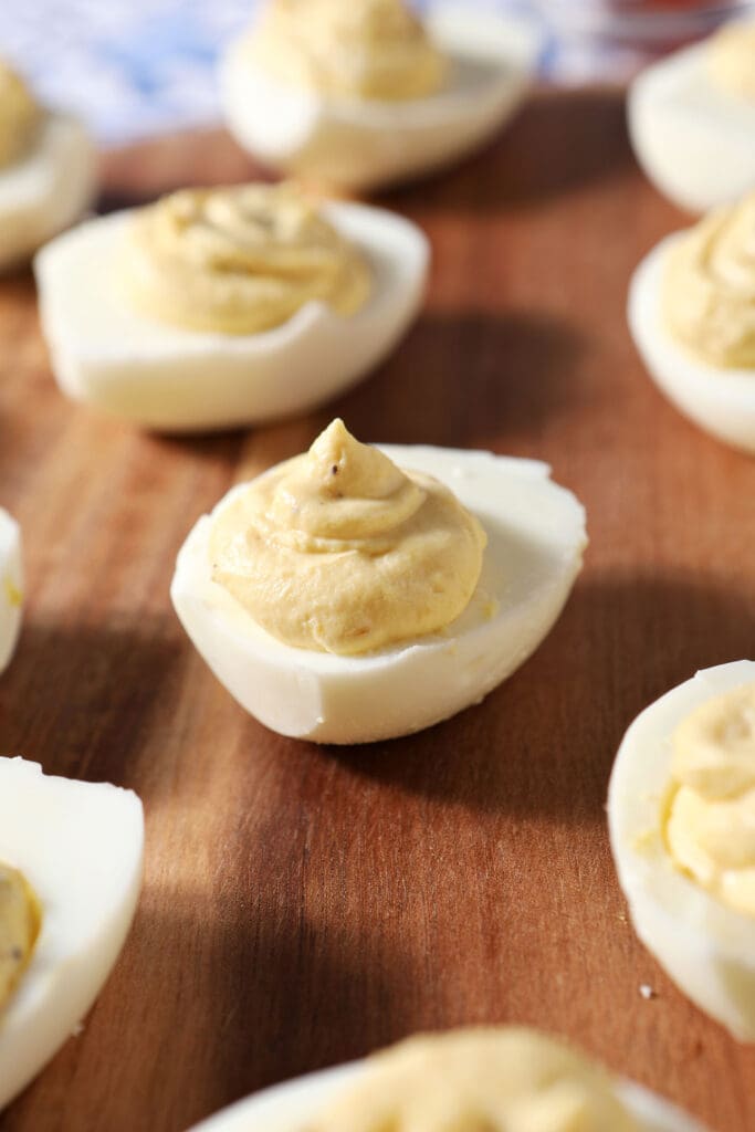 Deviled eggs on a wooden surface before garnishing