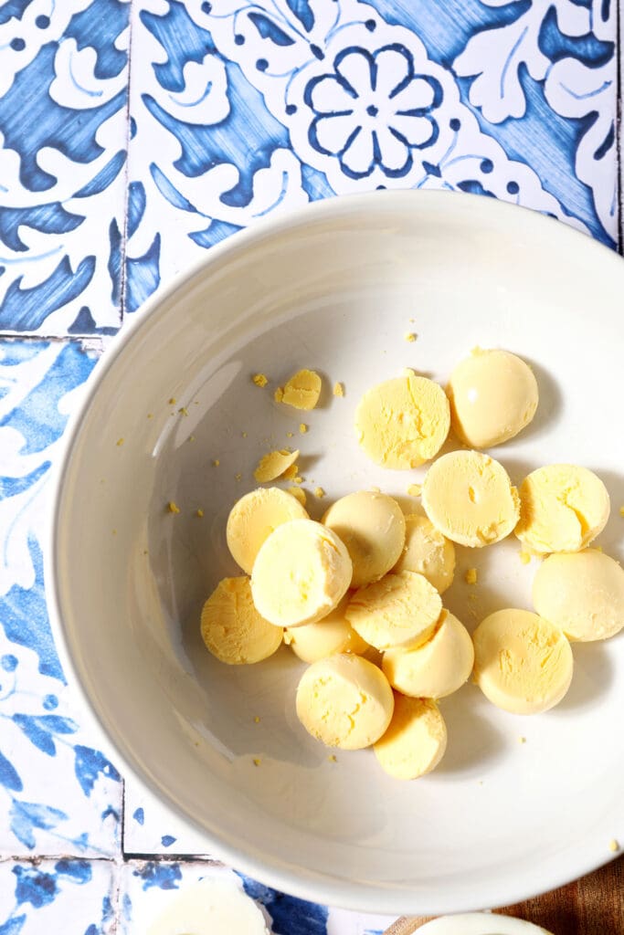 Egg yolks in a white bowl on a blue and white tiled surface