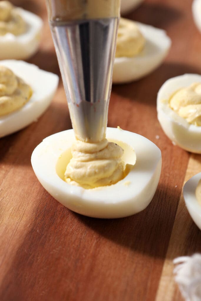 A piping bag fills an egg white to make a deviled egg